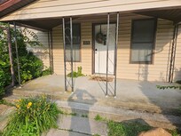 Nice location, weeds growing though porch and sides