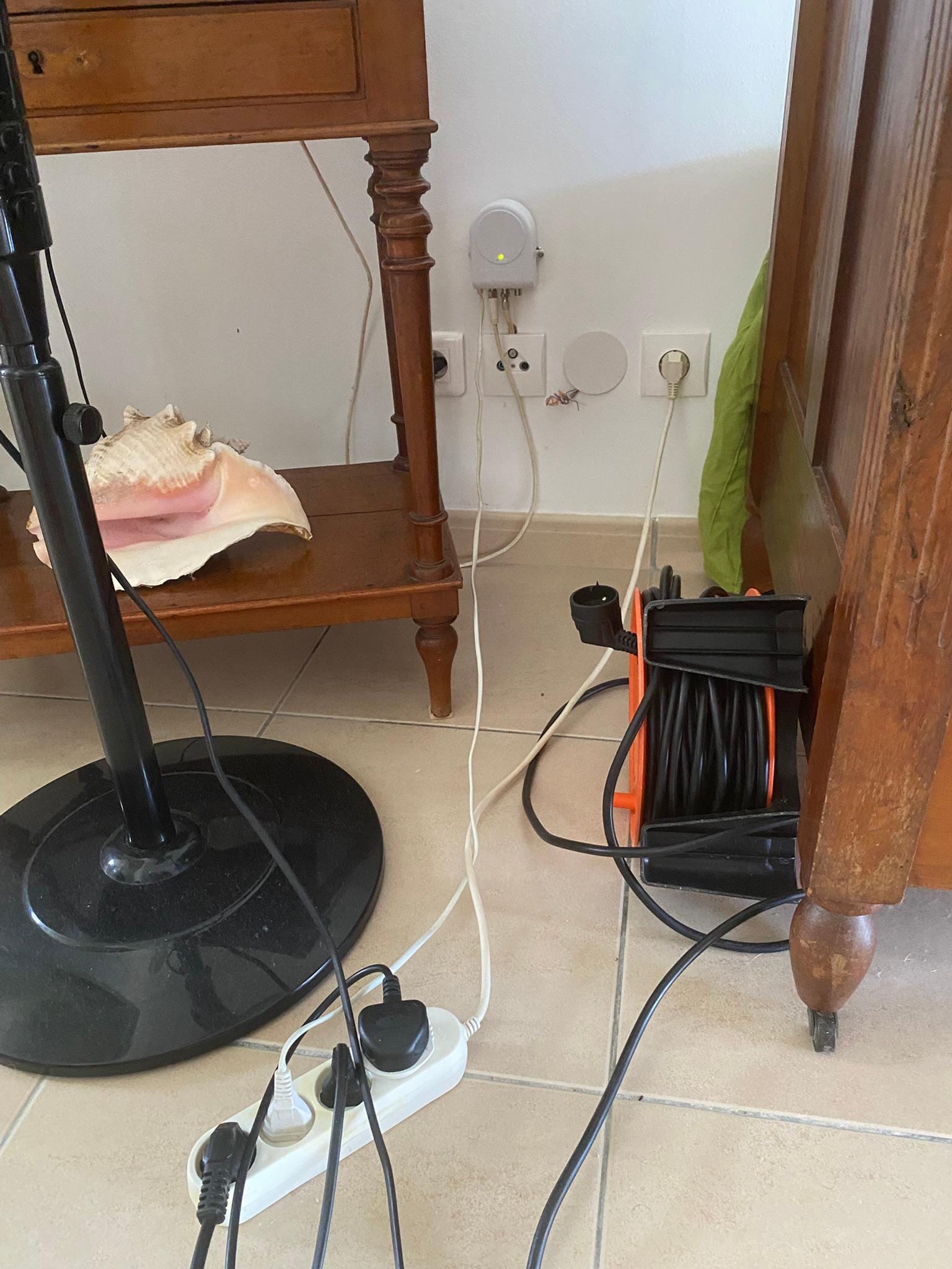 Exposed electrical wiring on wall and multiple extension cables feeding appliances