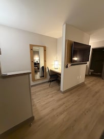 Desk area and small fridge on opposite wall.