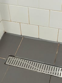 Black/pink mould contrasts with white grout, especially in corners