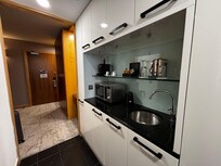 Fridge, nespresso, kettle, microwave and sink along with plates bowls and cutlery.