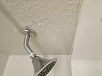 The shower head looks like it is falling out of the wall