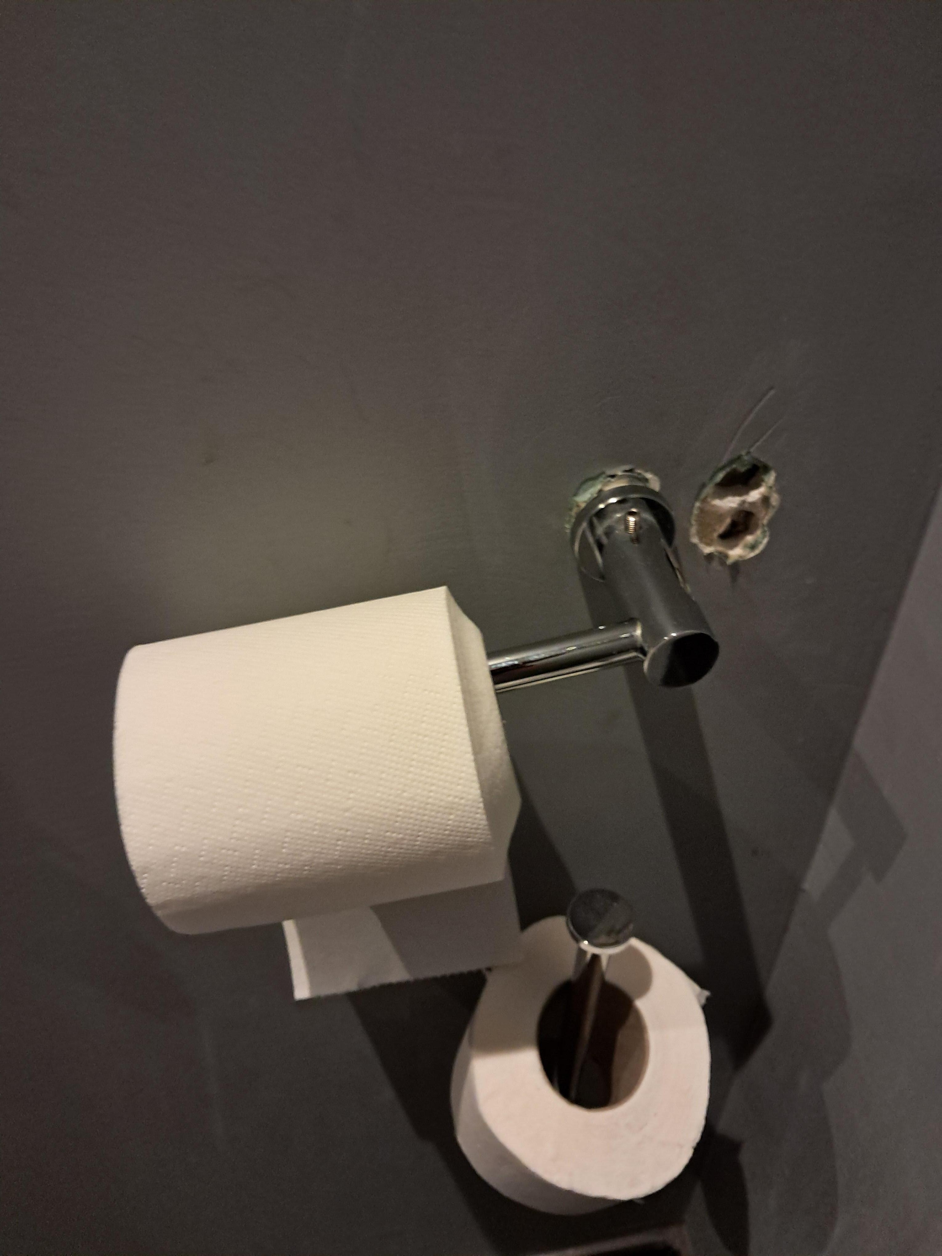 Hole in the wall with toilet holder hanging skew