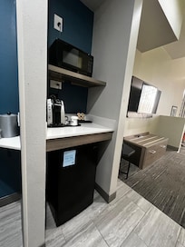 Small âkitchenâ area with refrigerator, microwave, coffee maker.