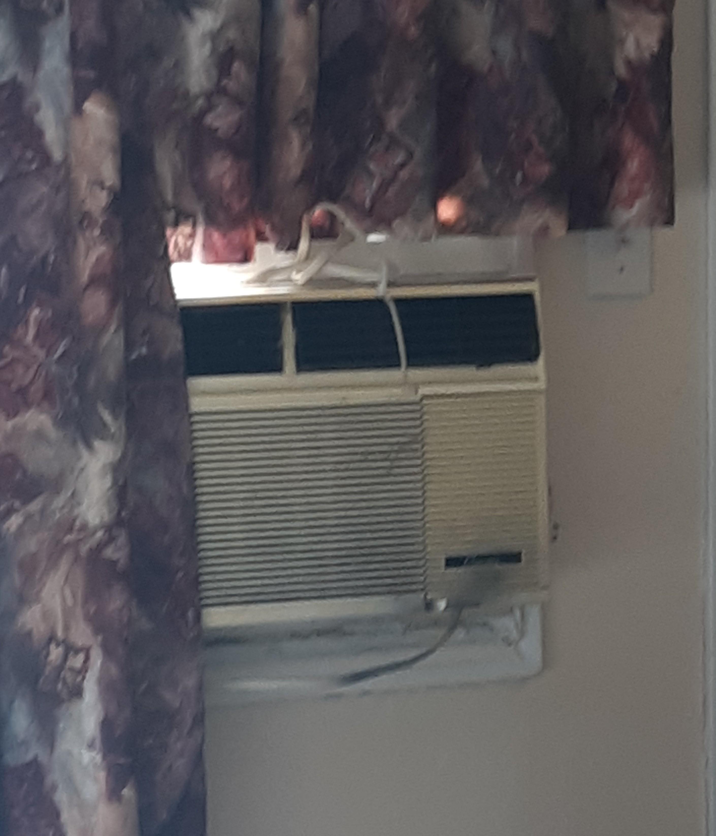 Old dirty air conditioner beside old curtains.