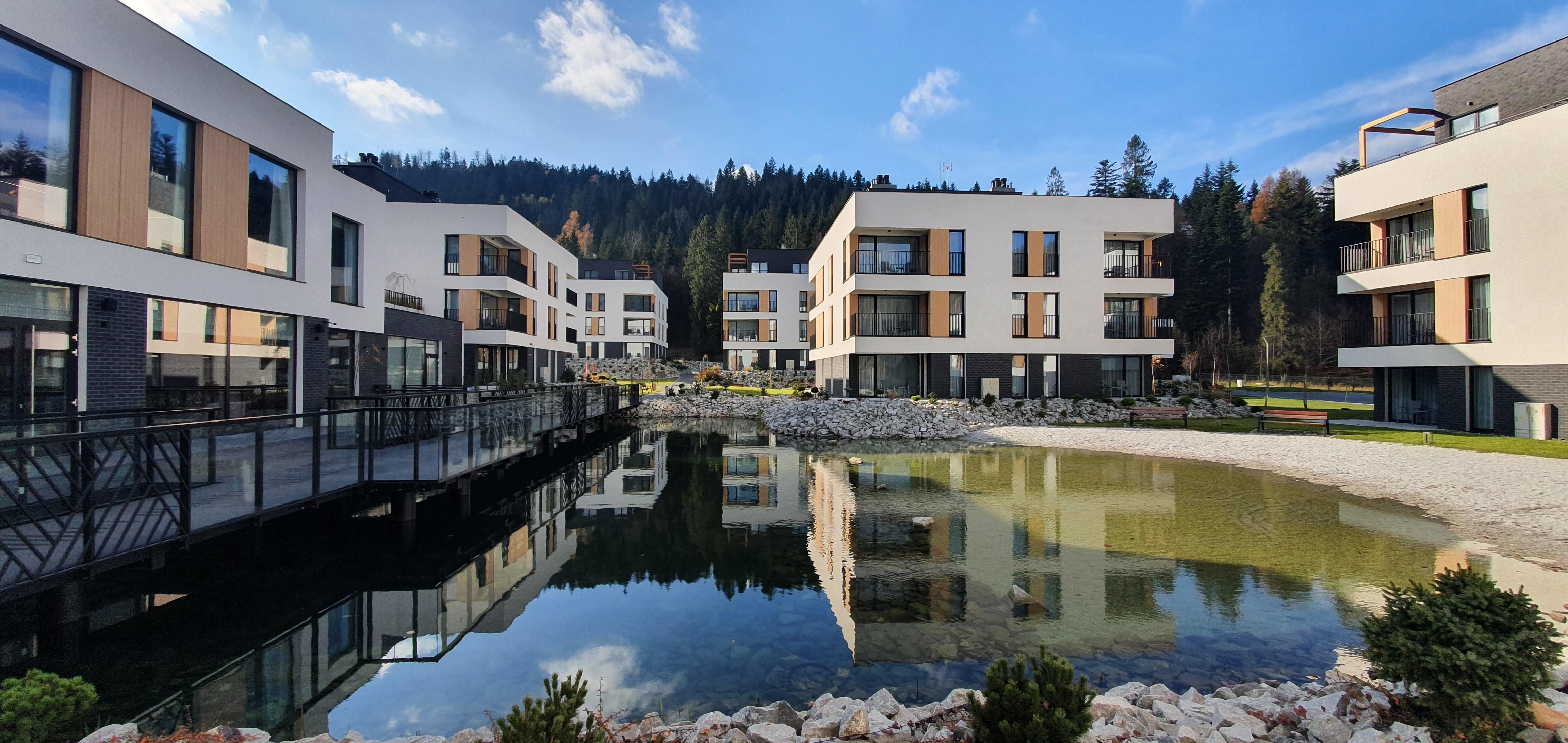 Centrum obiektu, po lewej recepcja, kawiarnia, restauracja, SPA i baseny. W koło budynki z apartamentami i oczywiście piękne jeziorko.