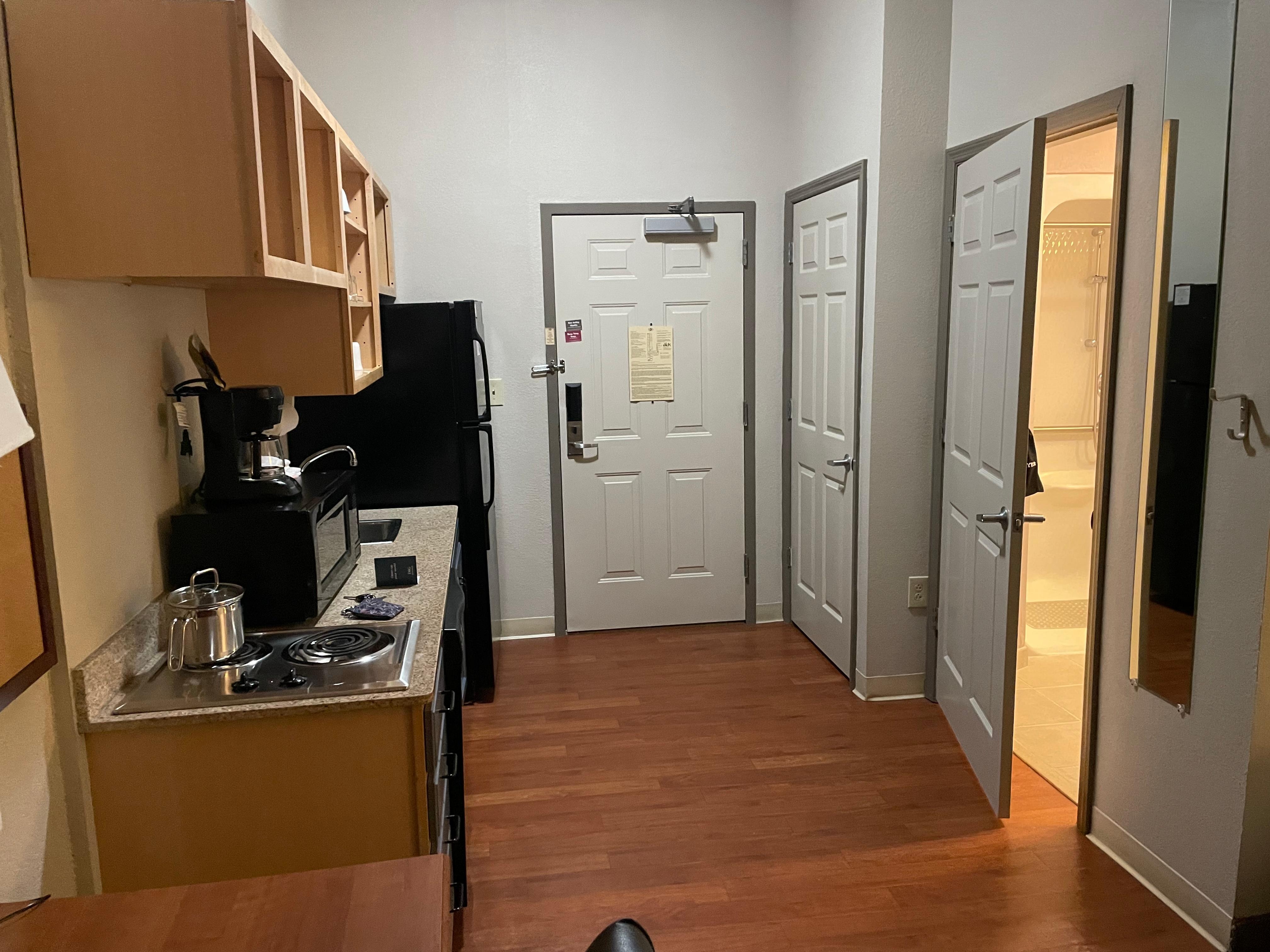 View of door/hall entrance & kitchen area. Closet space too. Bathroom door ajar on the right.