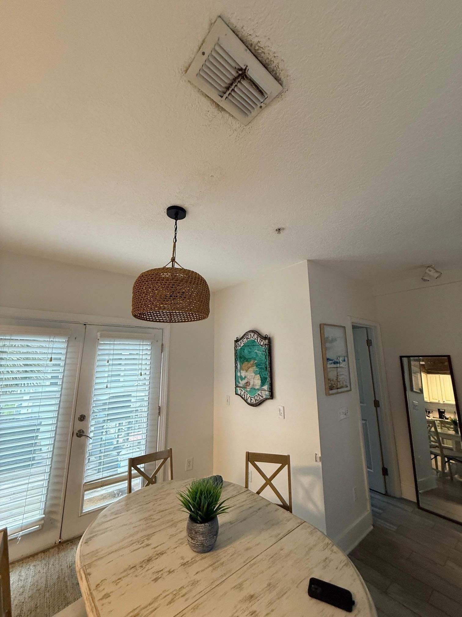 Dining room table with very moldy vent above table - with only 4 chairs with very dirty seats.