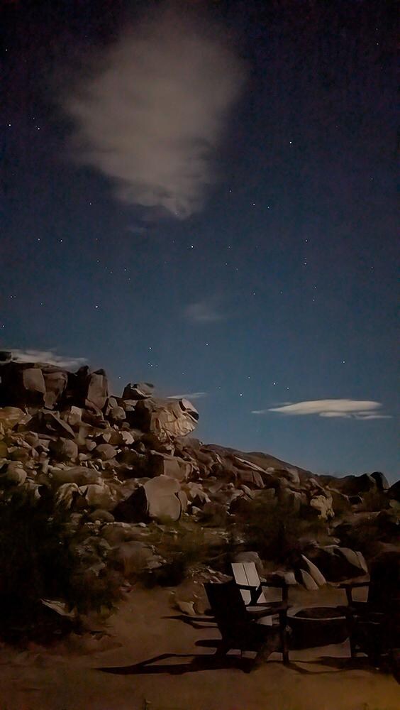 Backyard with chairs around the firepit, looking at the moonlit boulderscape.