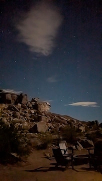 Backyard with chairs around the firepit, looking at the moonlit boulderscape.