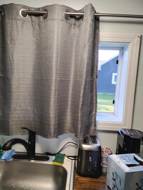 This is the kitchen window. Curtain has been chopped off at the bottom to make it fit.