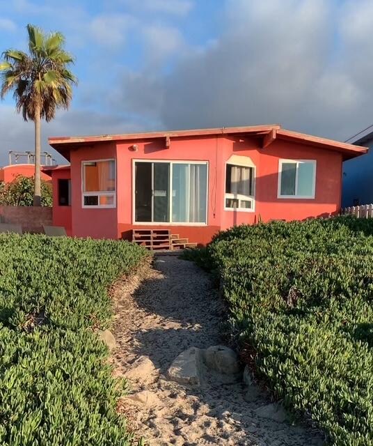 Such a cute house. You can't really see it in this photo, but there are two lounge chairs with a little table on the left, and two more chairs, a BBQ, and a fire pit on the right (all behind the ice plant, up by the house). 