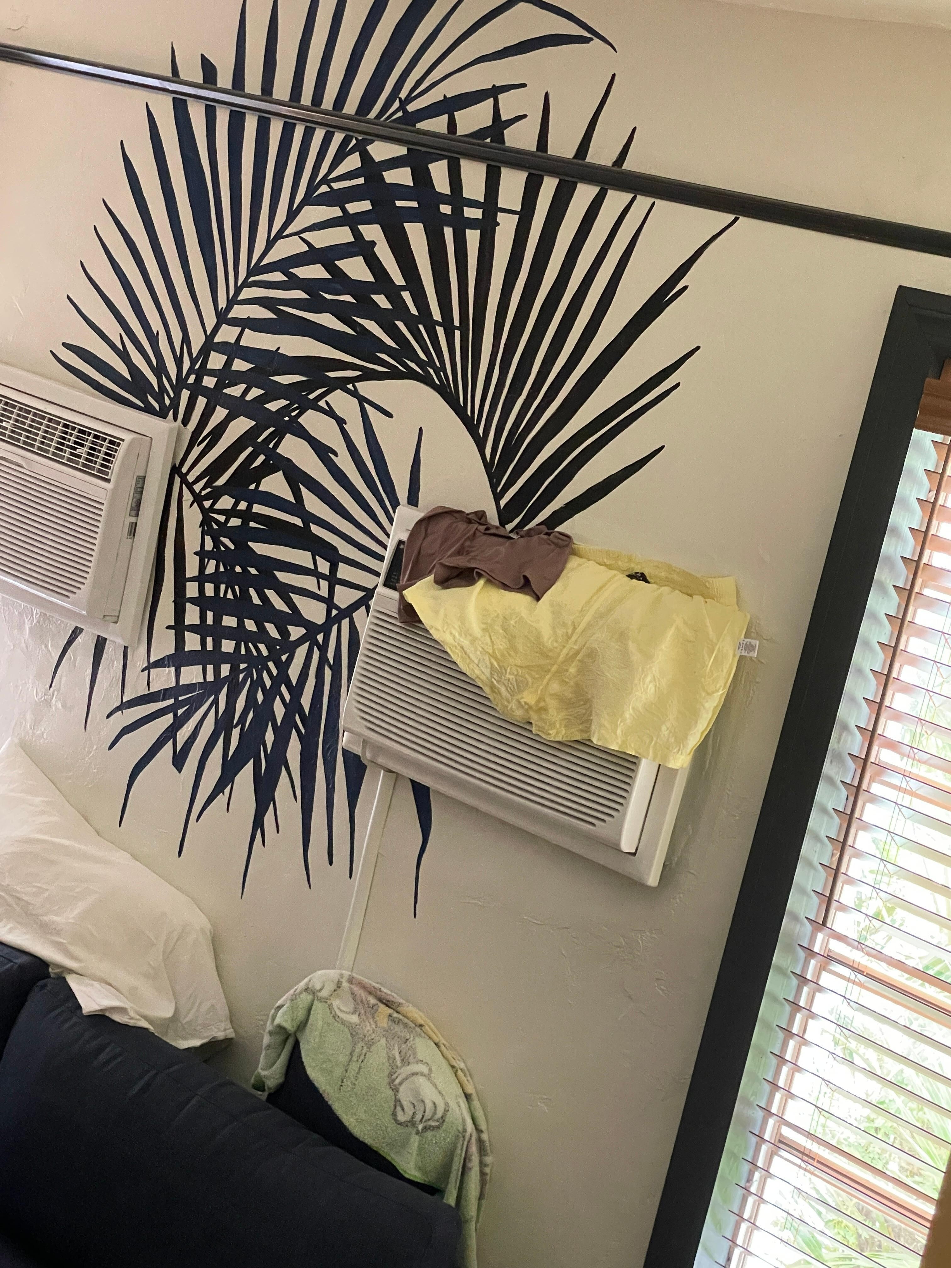 Shared hostel room where someone hangs their wet clothes from AC unit blocking air flow. 