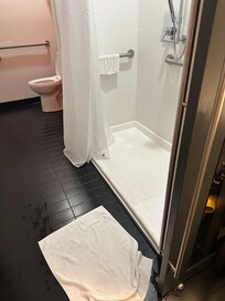 Shower head faces the corridor, which wets the floor (fall risk)