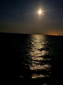 The luminous moon is positioned near the ocean.