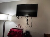 Actual room condition showing exposed, unsecured wiring hanging beneath the television