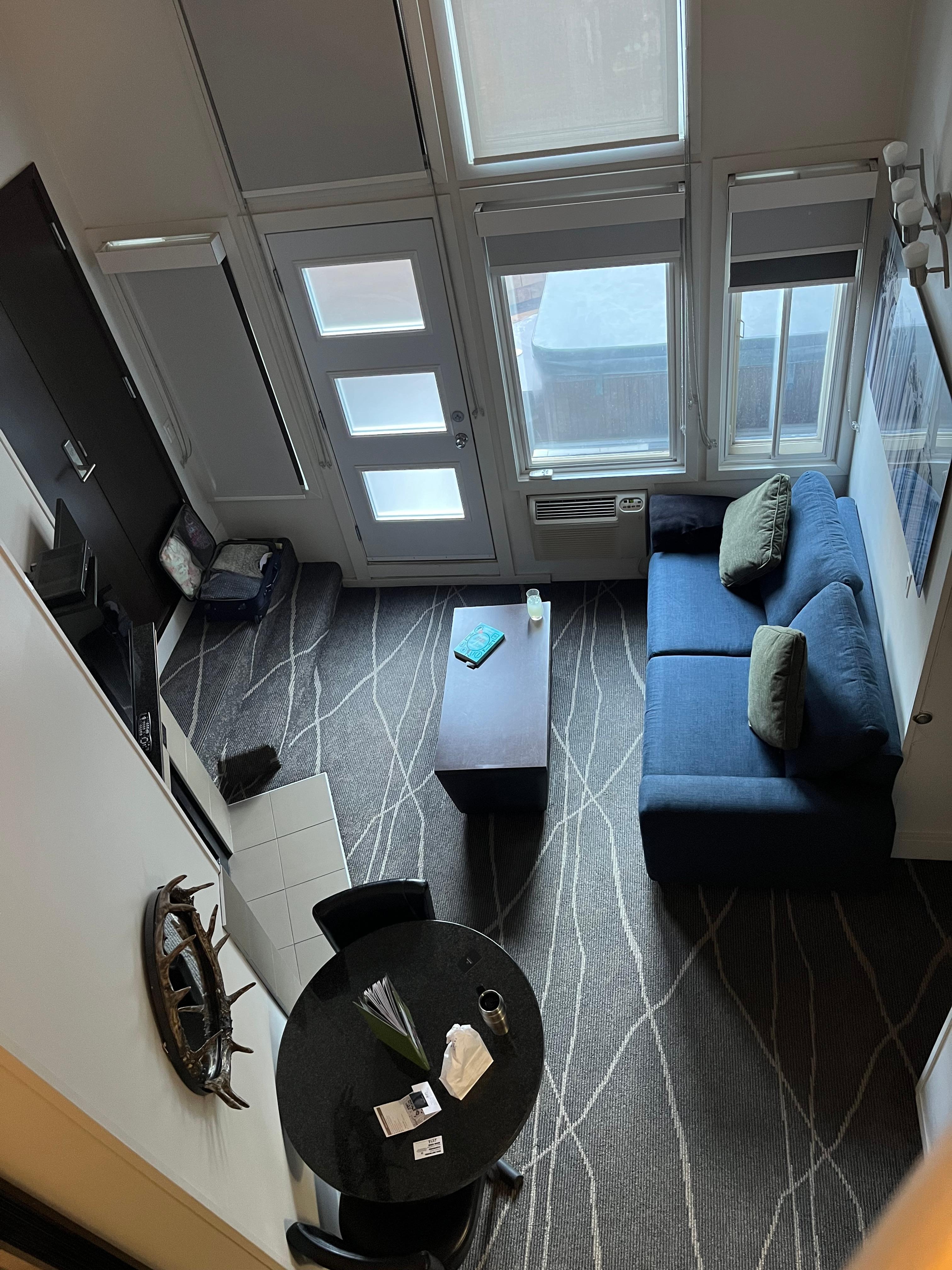 Comfy Queen bed in loft looking down into living room and out towards mountain view.