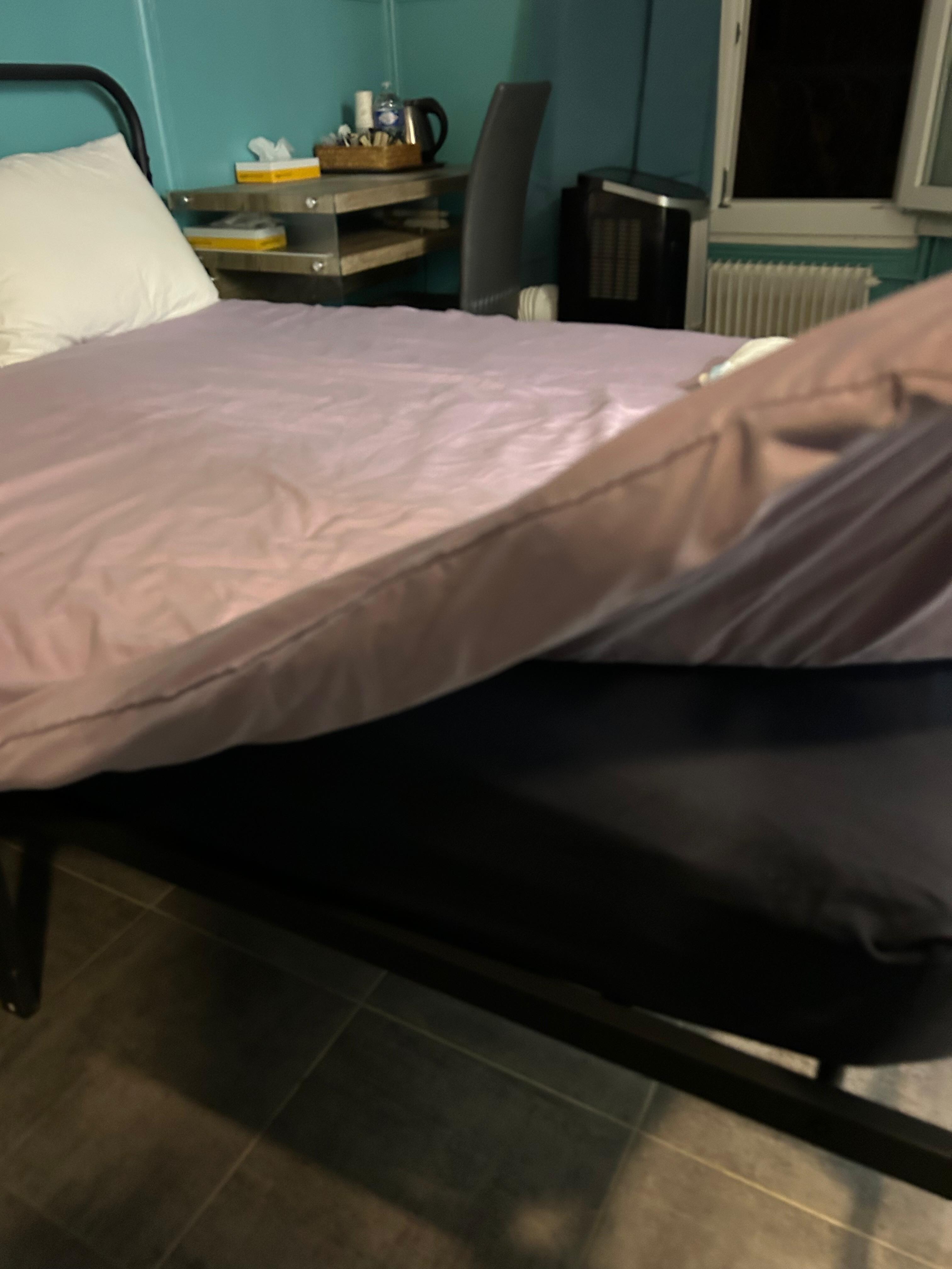 Metal bed with black mattress and wrinkled bed cover