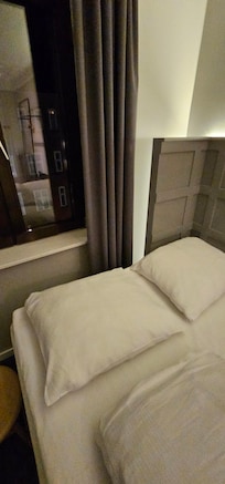 Small queen bed without backrest. For two (especially large) persons I recommend to book to single bed rooms.