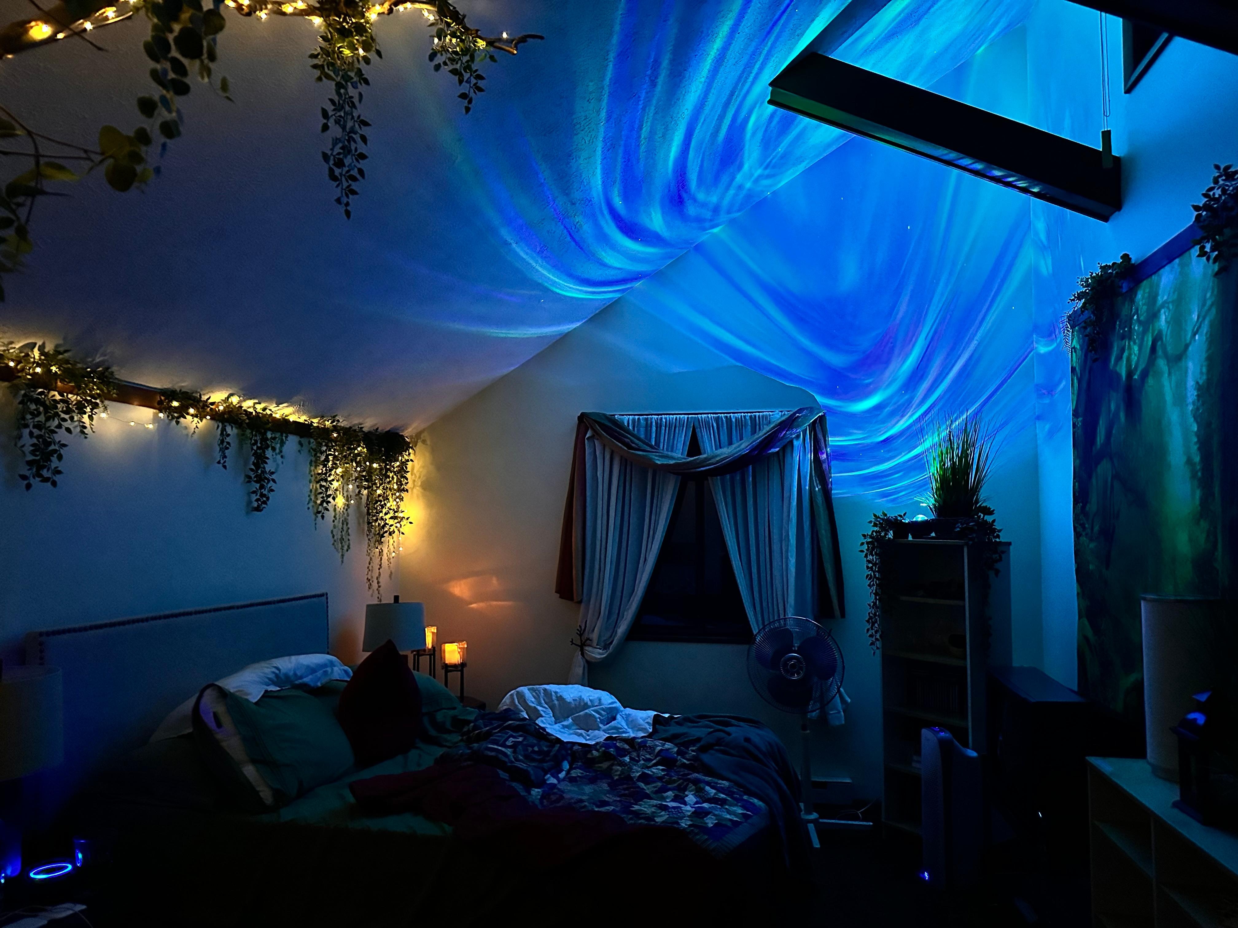 The main bedroom upstairs at night with forest backdrop, aurora light, and fairy lights along the ‘vine’ and ‘leaves’. So relaxing!! 