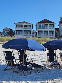 Beach chairs and umbrellas, house is the one on the left.