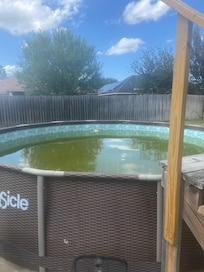 Above ground pool, brown water and trash in it..
