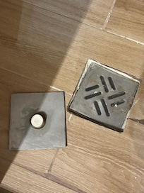 The shower floor with the cover for the drain removed.