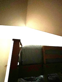 View of the 5 inch space between the ceiling and the ladder - making it impossible to use the ladder to get on the bed.