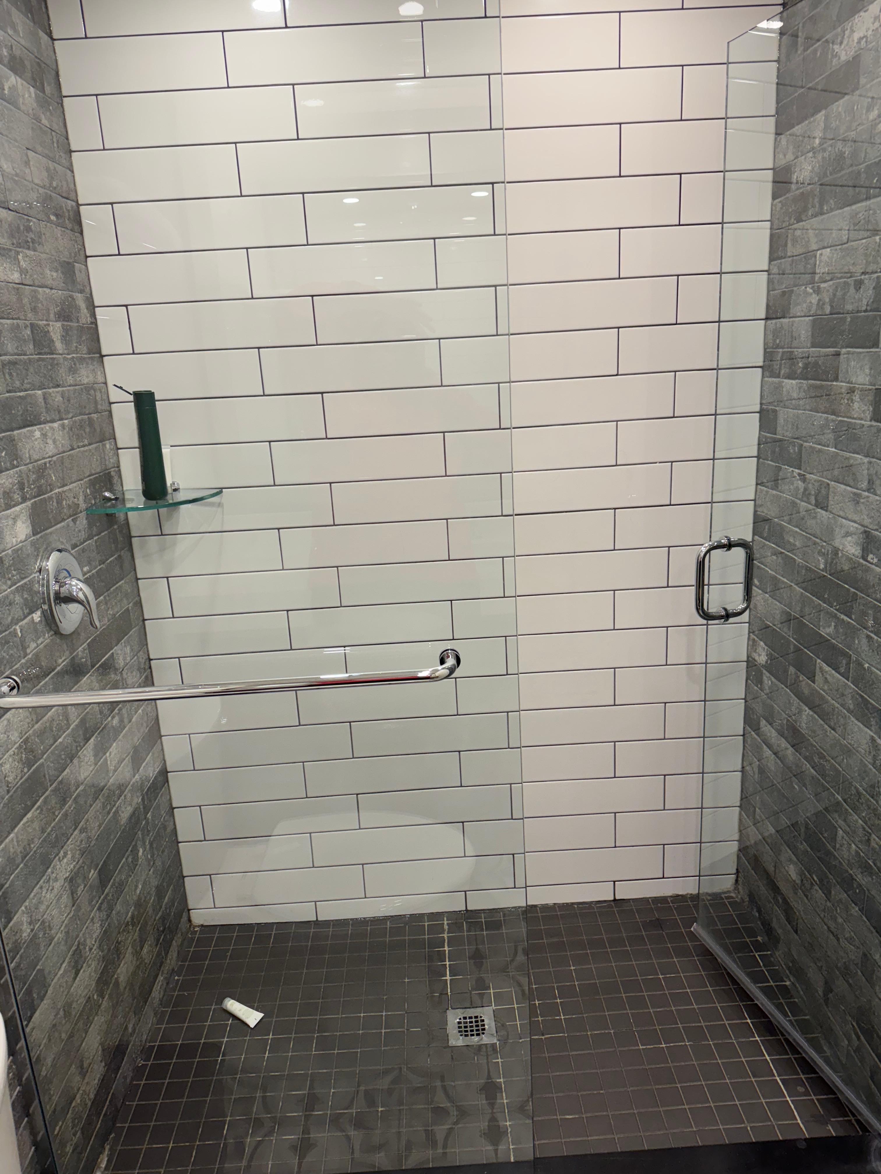 Shower has rain shower head and is modern.