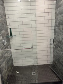 Shower has rain shower head and is modern.