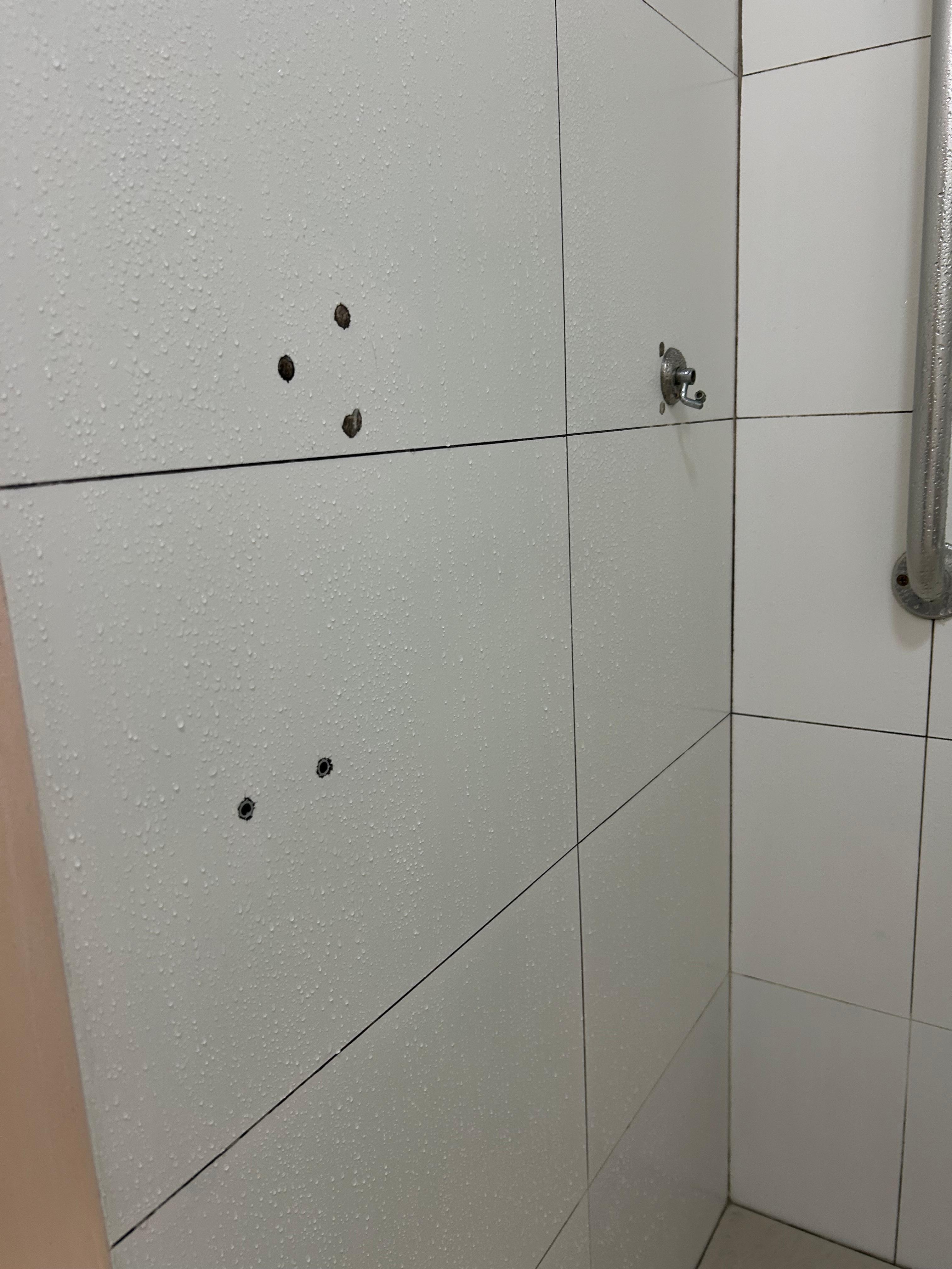 Banheiro com várias cerâmicas furadas 