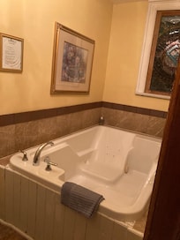 Separate room with jetted tub, an additional shower, and stained glass.
