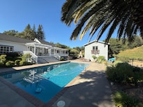 The lovely rear area of the property with gorgeous vineyard view, outside gas fireplace, bocce court, pool area, and separate cottage with pool table and bar!