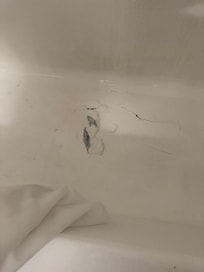 Hole in bottom of bathtub covered with duct tape and sealant