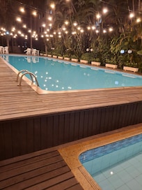 A piscina a noite é bem iluminada.