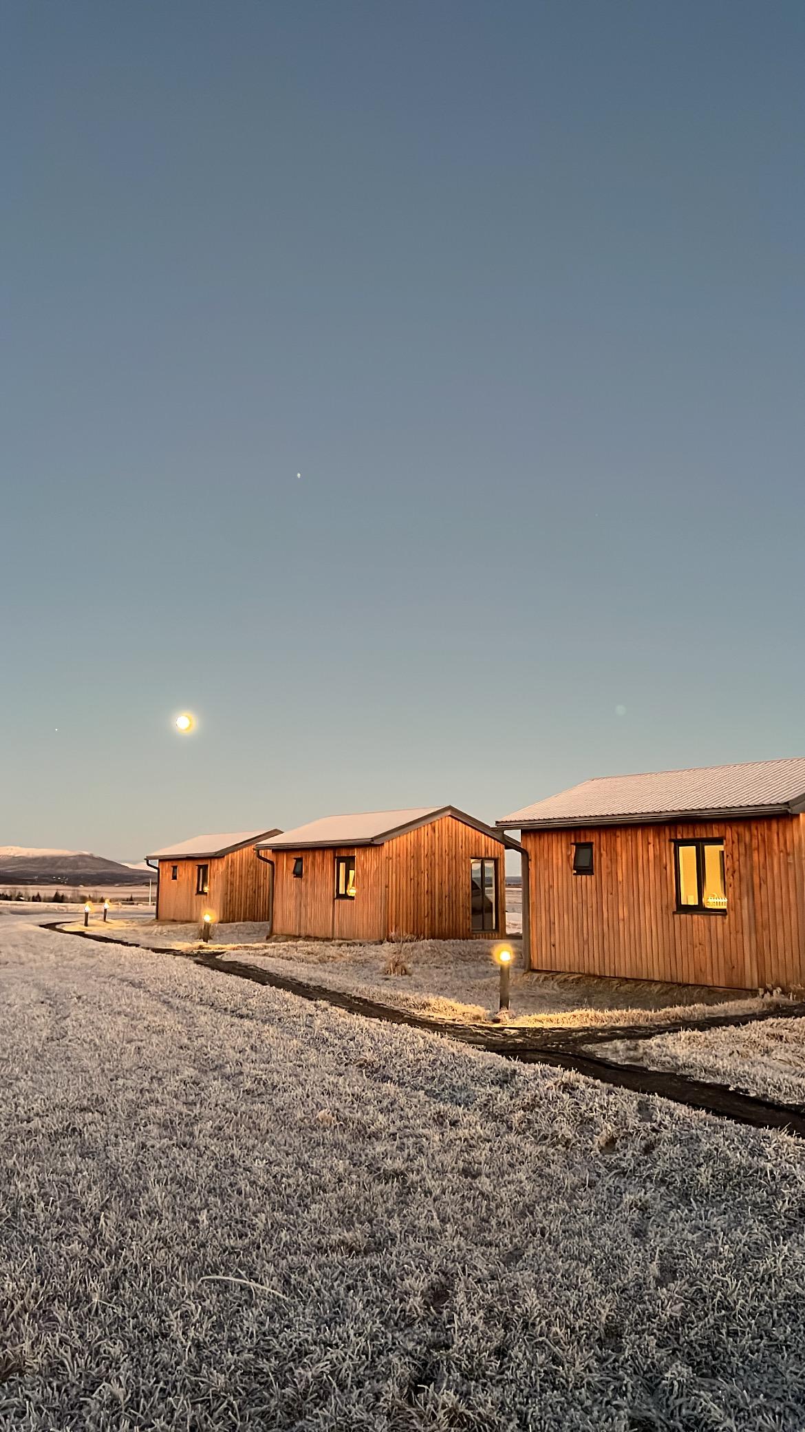 Cottages at night with the moon in the background.