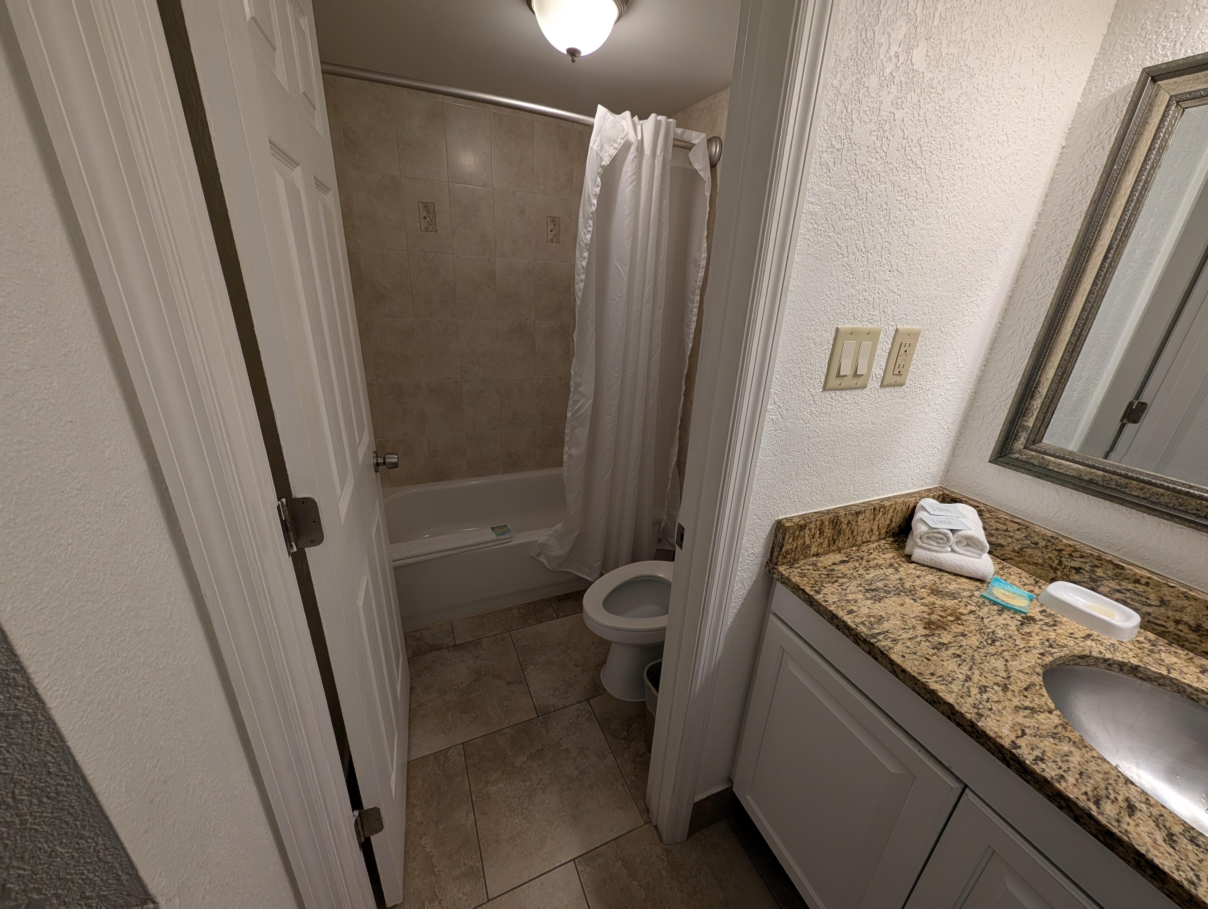 Tub/shower and toilet behind  a door.  sink in the open