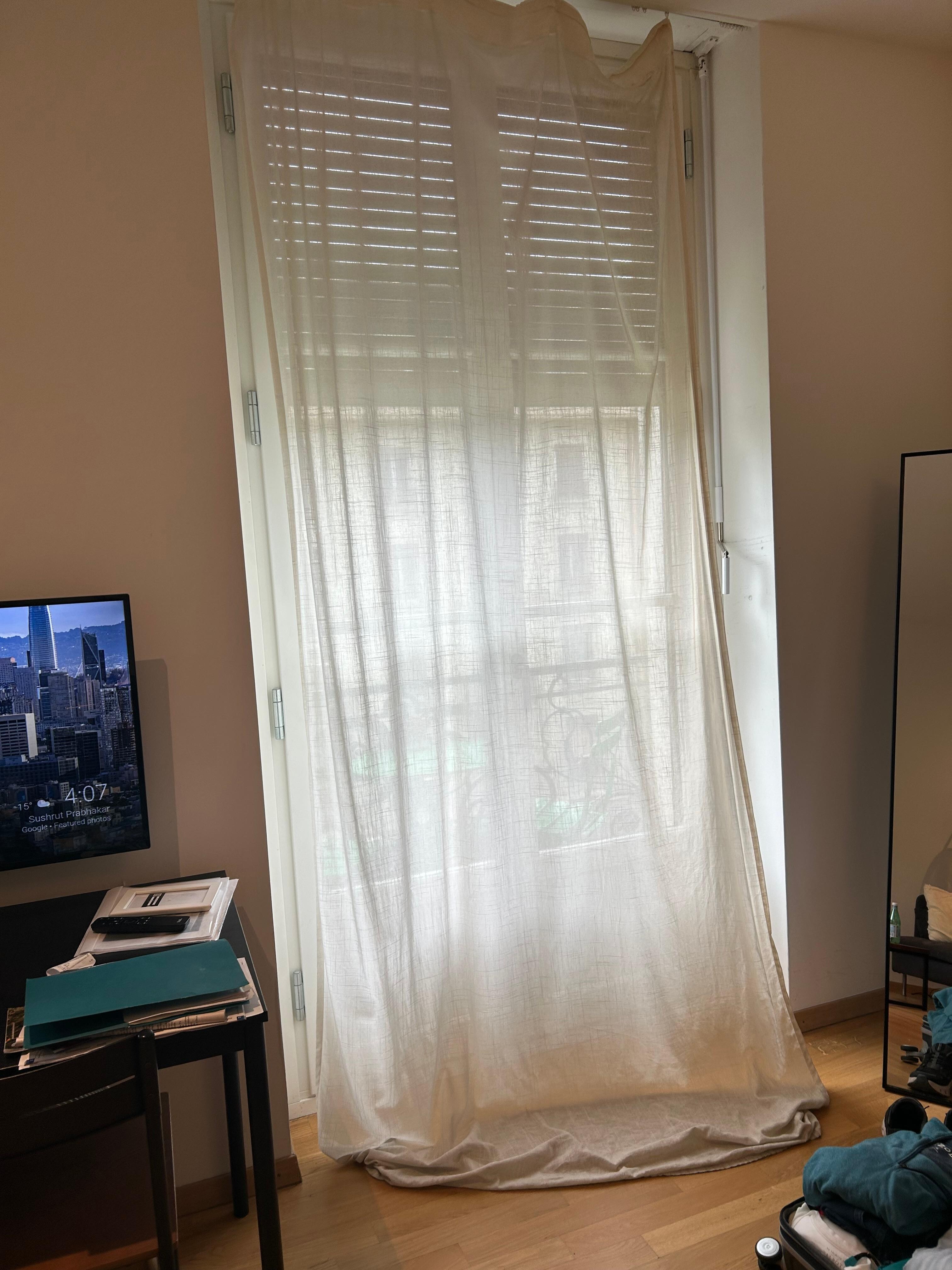 Curtain partially clipped and hung on floor over a foot too long. 