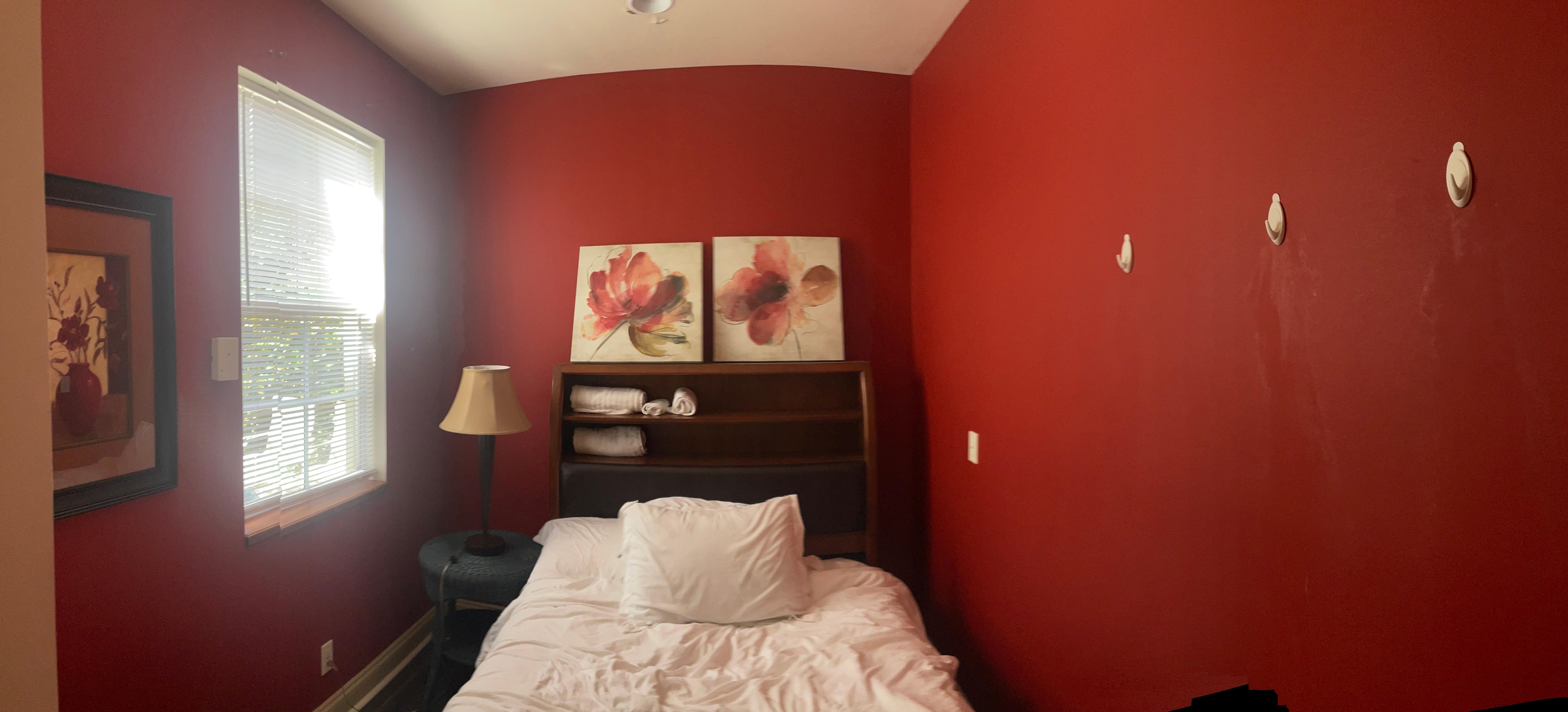 Room with peeling paint, hooks for clothes. Very tight to walk around. 