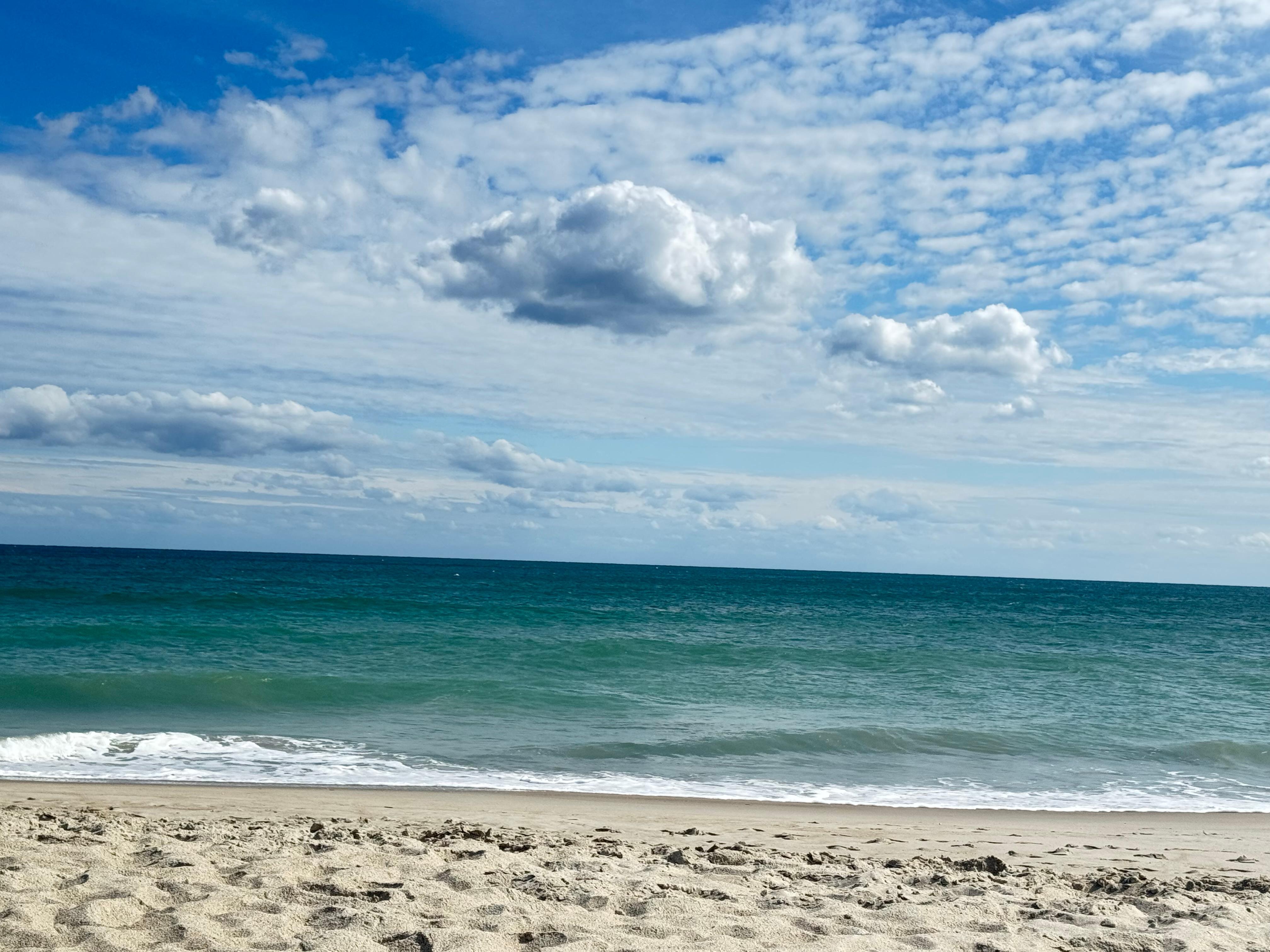 Gorgeous Emerald green water against suspended puffy clouds and sand!