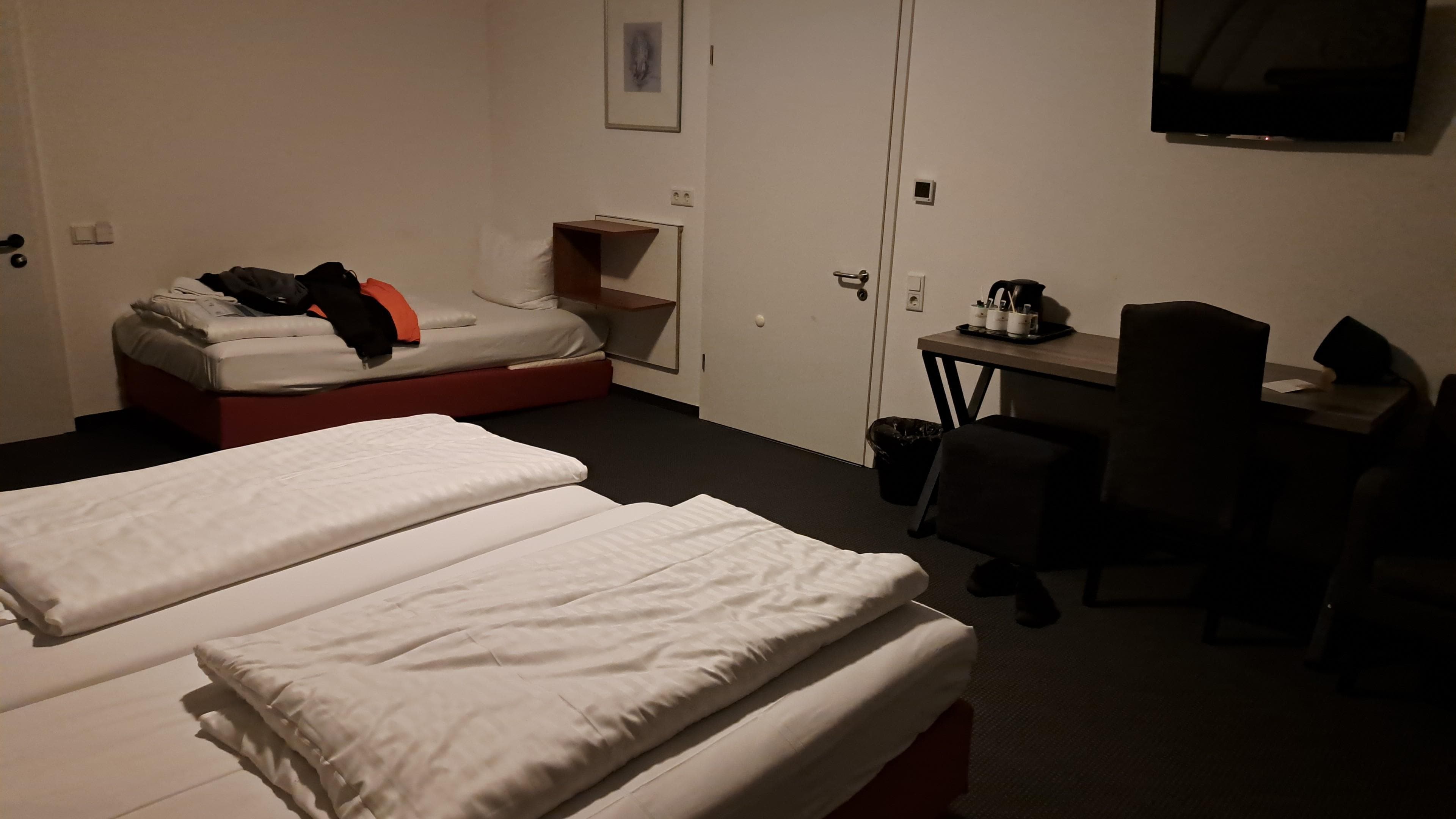 Zimmer mit Doppelbett und Einzelbett.