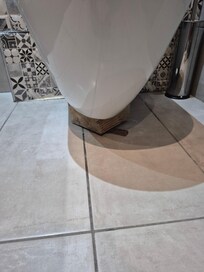 Wood jammed under toilet to stop it falling off wall