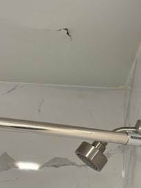 Hole ceiling above the shower head. Probably leak from the room above us. Which caused the damage