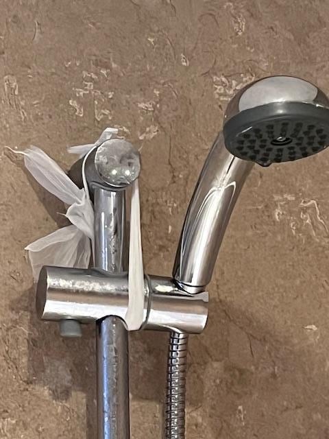 pommeau douche tenu par un sac plastique