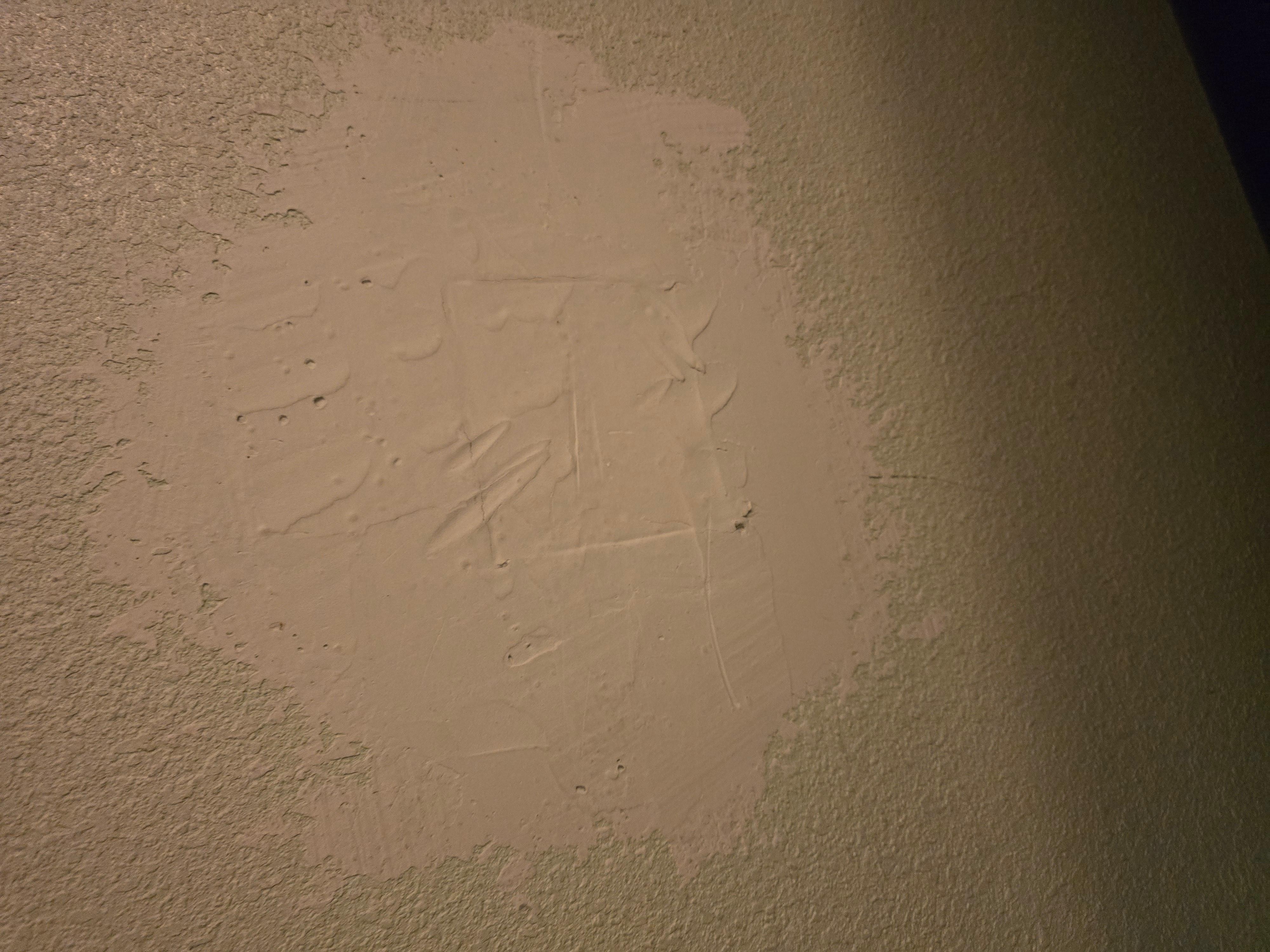 Unfinished drywall patch near bed