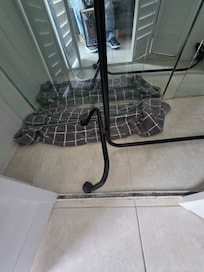 Broken shower door is placed in the closet on a towel.