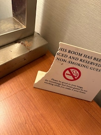 Cracked sign. No smoking with cigarette ash on the counter