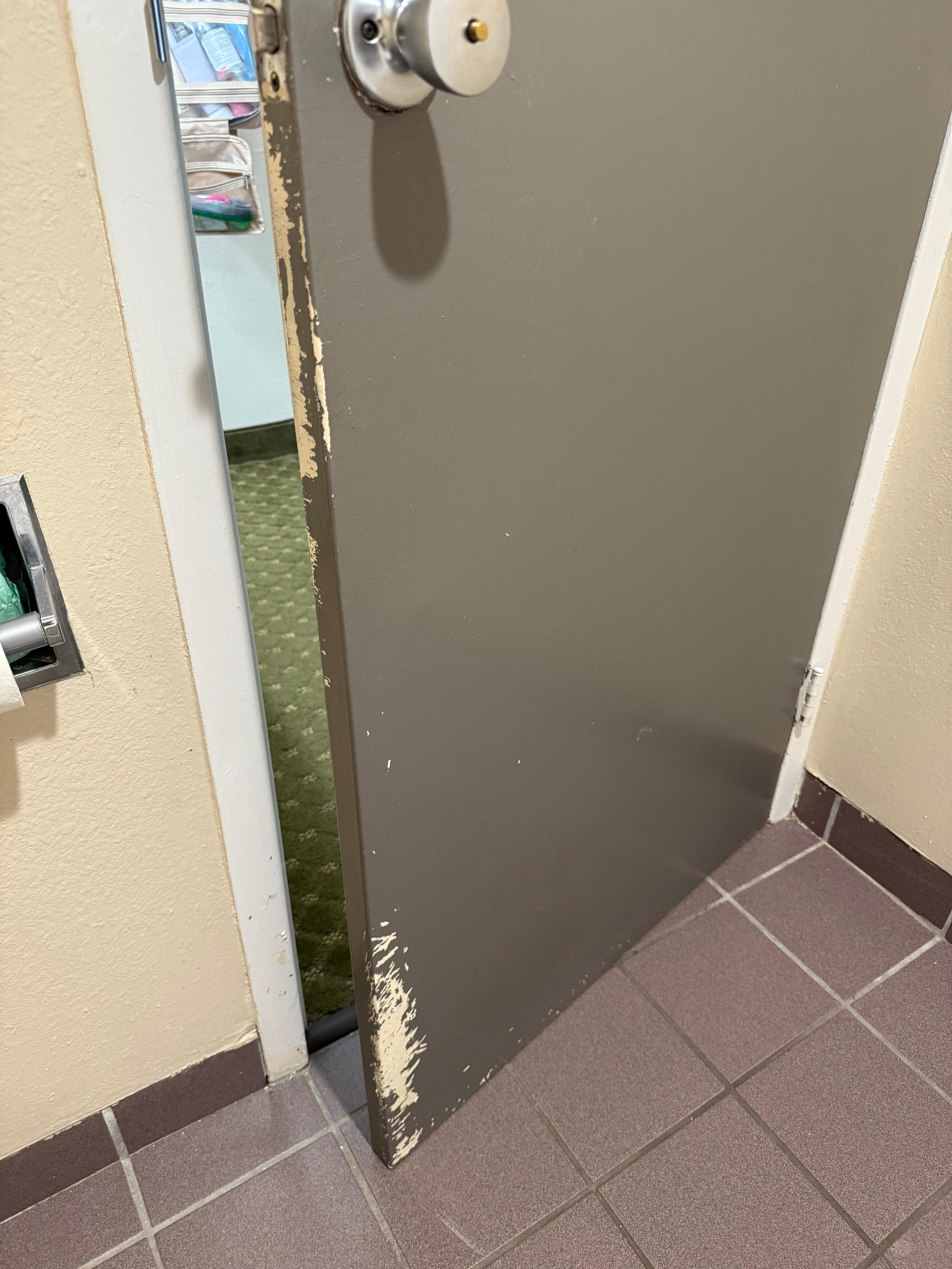 This bathroom door does not close and is all torn up.