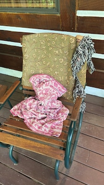 A blanket left in the porch rocking chair as if someone had just left