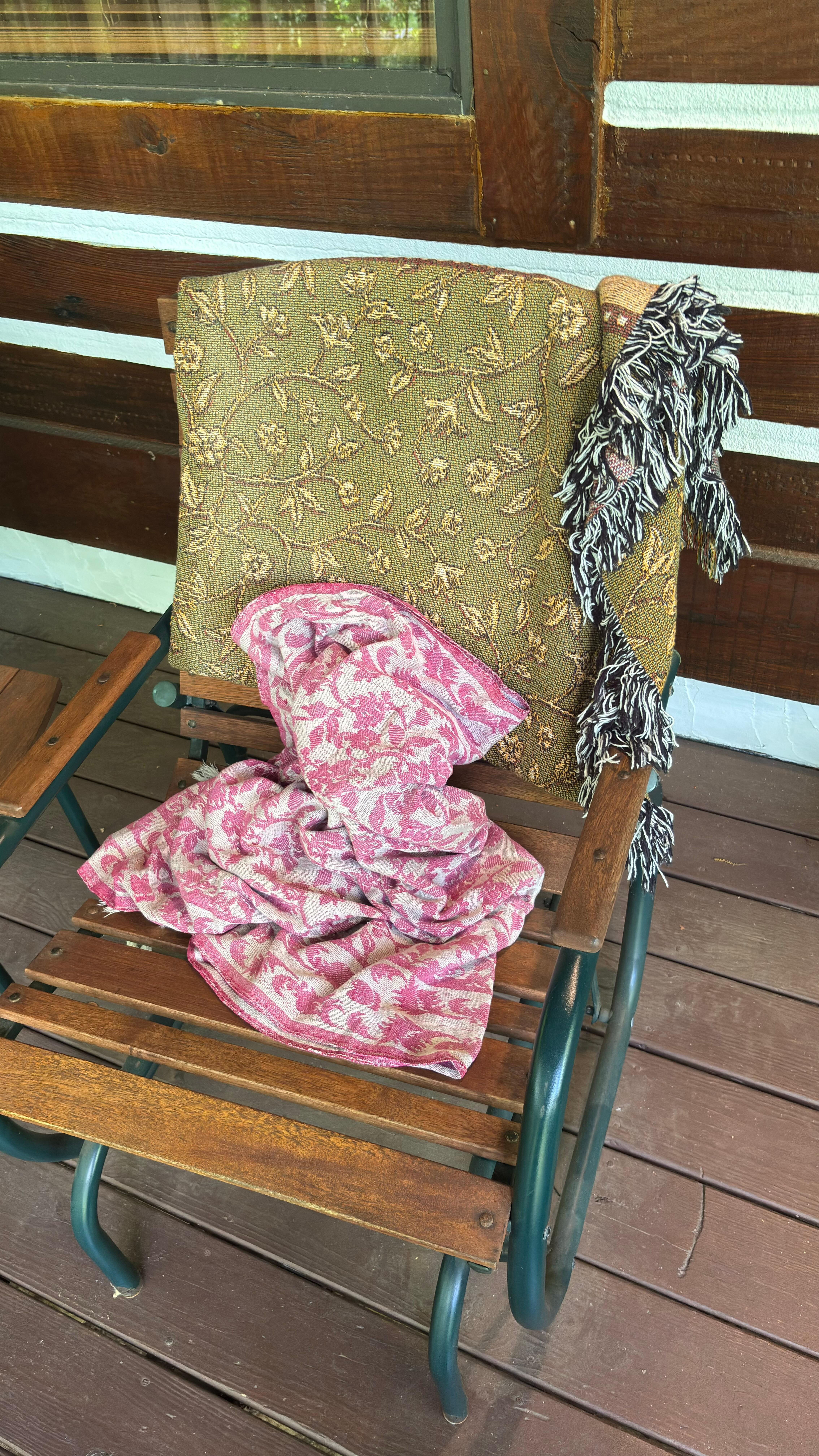 A blanket left in the porch rocking chair as if someone had just left